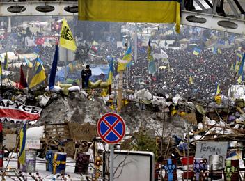 A dense crowd of protesters fill the streets beyond a barricade in Kiev