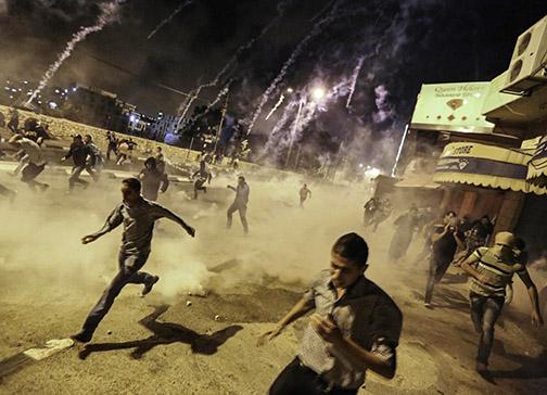 Palestinians in the West Bank run from an Israeli bombardment of tear gas