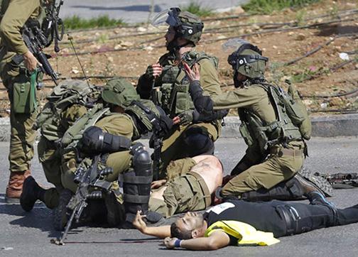 Israeli soldiers surround the body of the Palestinian man they shot