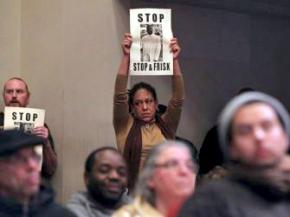 Protesters stand against William Bratton during an Oakland City Council meeting