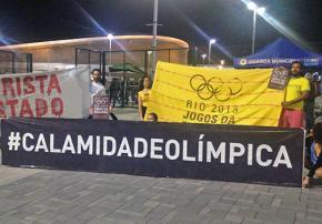 Activists from Rio's Vila Autódromo hold their banners outside the Olympic Stadium